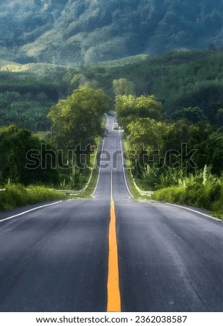 The picture showcases a straight road with a yellow line running down its center. The road appears well-maintained and is surrounded by open space or perhaps countryside scenery.  Royalty-Free Stock Photo #2362038587