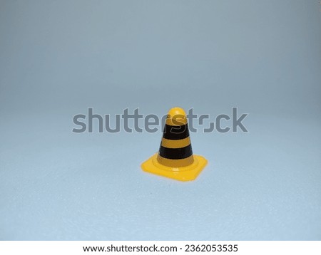 focus on a small yellow cone with black stripes. It is on a blue base