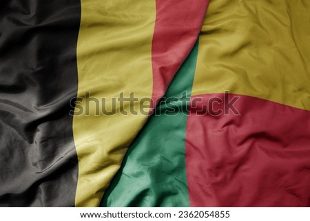 big waving national colorful flag of belgium and national flag of benin . macro