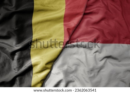 big waving national colorful flag of belgium and national flag of indonesia . macro