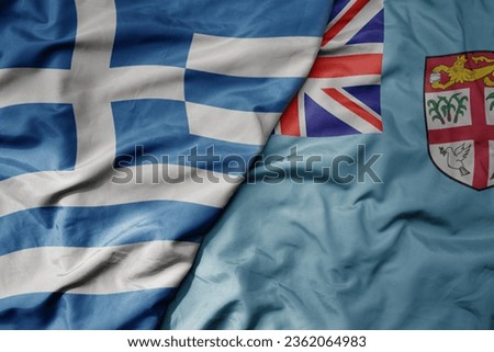 big waving national colorful flag of greece and national flag of Fiji . macro