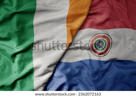 big waving national colorful flag of ireland and national flag of paraguay . macro