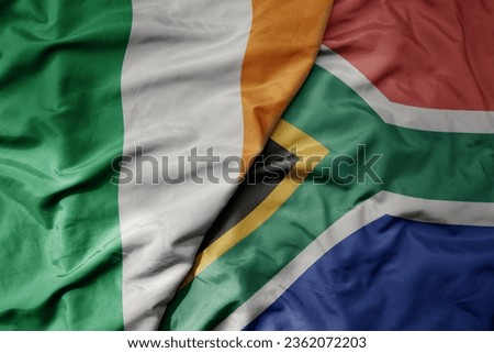 big waving national colorful flag of ireland and national flag of south africa . macro