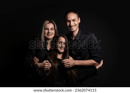 cute little girl and her beautiful young parents looking at camera and smiling