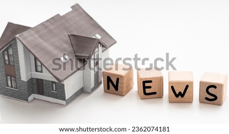 Real estate news symbol. Wooden blocks form the words 'Real estate news', miniature house, wooden table. Beautiful white background, copy space. Business and real estate news concept.