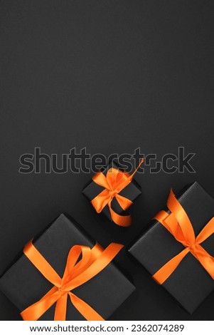 Black gift boxes with orange ribbons on a black background. Space for your text.