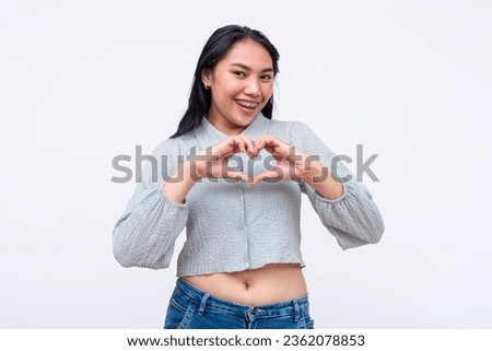 A young and lively asian woman making a heart shape with both hands. Isolated on a white background. Royalty-Free Stock Photo #2362078853