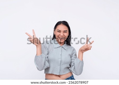 A lively and exuberant young asian woman makes a double peace sign. Feeling upbeat and elated. Isolated on a white background.