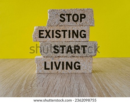 Stop existing start living symbol. Concept words Stop existing start living on brick blocks. Beautiful wooden table yellow background. Business Stop existing start living concept. Copy space. Royalty-Free Stock Photo #2362098755