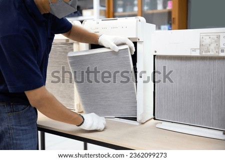 Technician open cover to fix and holding dirty and dust air purifier filter for removing and change. Concept of pm2.5 air pollution clean or heat maintenance air conditioner service repair. Royalty-Free Stock Photo #2362099273