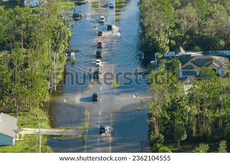 Flooded road in Florida after heavy hurricane rainfall. Aerial view of evacuating cars and surrounded with water houses in suburban residential area Royalty-Free Stock Photo #2362104555