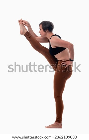 Utthita hasta padangusthasana (Extended hand to big toe pose), Ashtanga yoga. Side view of woman wearing sportswear doing Yoga exercise against white background.  Royalty-Free Stock Photo #2362109033