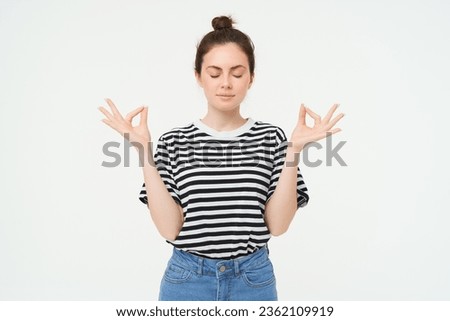Keep calm and meditate. Young woman relaxing, standing in asana, zen pose, holding hands sideways and meditating, standing over white background.