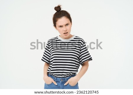 Image of woman looking with arrogant, frustrated face, frowning and staring at you with bothered threatening expression, standing over white background. Royalty-Free Stock Photo #2362120745