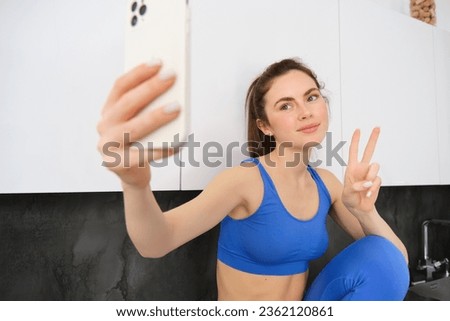 Fit and healthy young sports woman, showing peace sign, taking selfie in activewear, fitness blogger making photos for social media in her activewear.