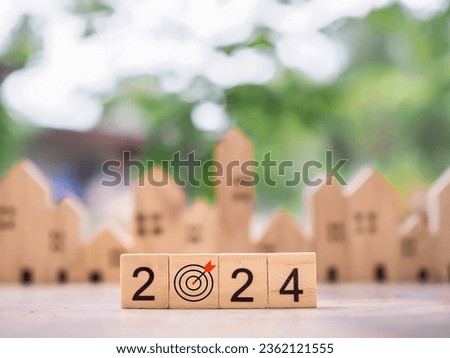 Wooden block with 2024 and goal business icon with miniature house background. Property investment, House mortgage, Real estste, Family concept