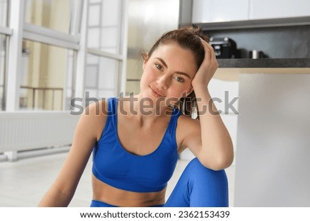 Portrait of sportswoman doing workout at home, smiling and looking at camera.