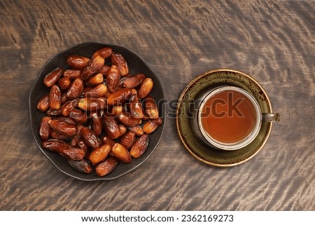 Dates and a cup of tea on a wooden background. Popular food for Ramadan. Top view, flat lay.