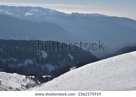 Mountain peaks in the snow are illuminated by the sun. View of the slopes covered with snow. Cold morning.