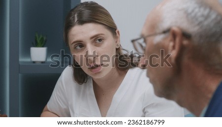 Female doctor sits in clinic cafe with elderly patient. Professional medic discusses medical diagnostic results with senior man. Medical staff work in hospital or medical center canteen. Slow motion.