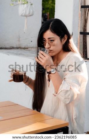 Girl enjoying and tasting coffee from the glass in a coffee shop