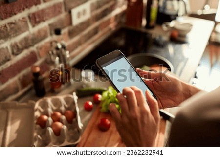 Young woman using a smartphone while preparing a healthy and organic breakfast in the morning