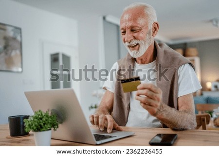 One man senior caucasian male grandfather sit at home use credit card and laptop computer shopping online use internet for online purchase active modern senior