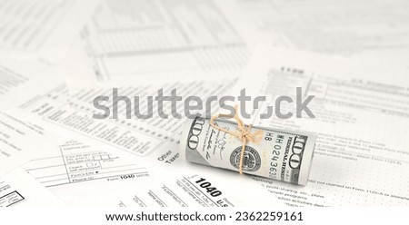 1040 Individual income tax return form with roll of american dollar banknotes close up. Concept of tax period in United States