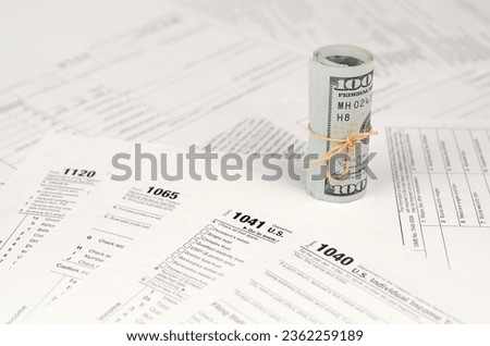 Tax forms lies near roll of hundred dollar bills. Income tax return. Time to pay taxes concept. 1040 1041 1120 and 1065 empty blank forms Royalty-Free Stock Photo #2362259189
