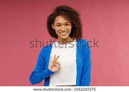 Cheerful woman showing sign Okay with smile while standing over pink studio background