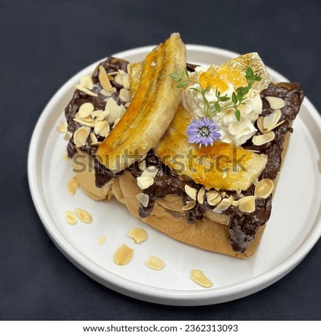 Banana french toast with whip cream, mint, and yellow flower on a white dishes . topping fresh banana and hokkaido milk ice cream, Black background, Picture free space for text