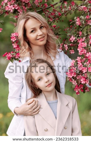 Mother and daughter under cherry blossoms, a serene family scene. Ideal for spring-themed promotions and family-oriented content.