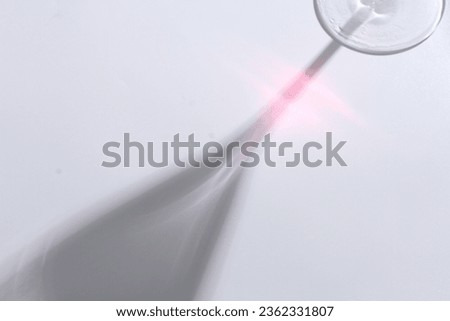 the shadow of a glass filled with colorful water on a white background
