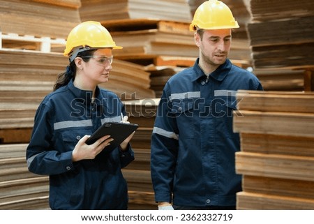 Two male and female employees are checking cardboard boxes in a warehouse for an export business.