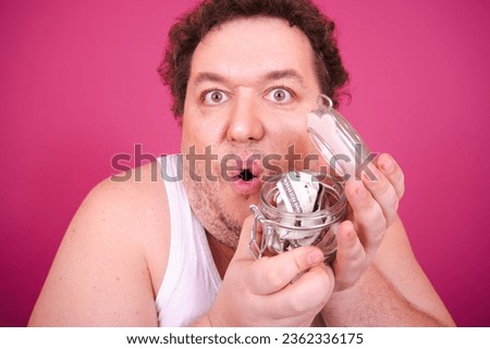 Funny fat man posing on a pink background. The poor man saves money.