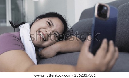 Fat Asian woman taking selfie with smartphone on sofa after exercising