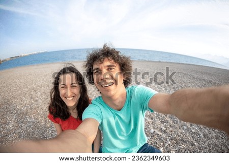 A man and a woman take a selfie on the seashore, a family rests on the sea, lovers take a photo on the beach