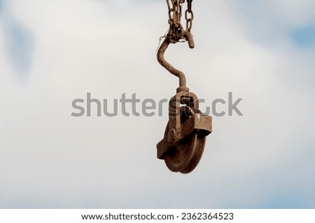 A rusty block hanging from a barn beam against the sky. Lifting loads to the attic (first floor). Royalty-Free Stock Photo #2362364523