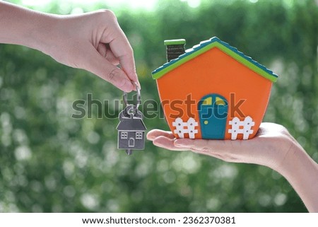 Purchase house, Woman holding model house and real estate agent giving a key on natural green background, New home and Real estate trading concept