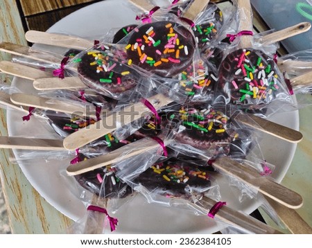 photo of dry chocolate cake with a wooden stick wrapped in plastic. chocolate cake pops. today's children's snacks.