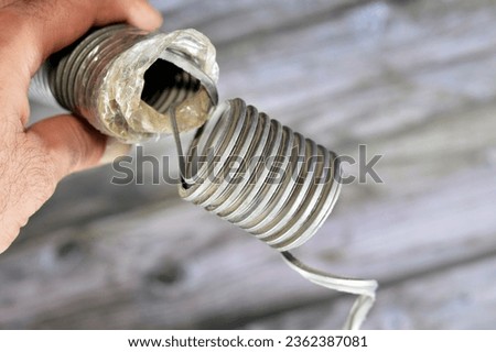 A broken flexible hose from a vacuum cleaner, substandard materials and maintenance services concept, a vacuum cleaner is an electrical house machine that collects dust and dirt by suction pressure Royalty-Free Stock Photo #2362387081