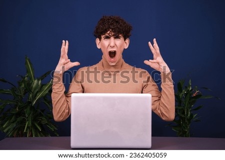 Funny curly guy working at a laptop. Blue background.