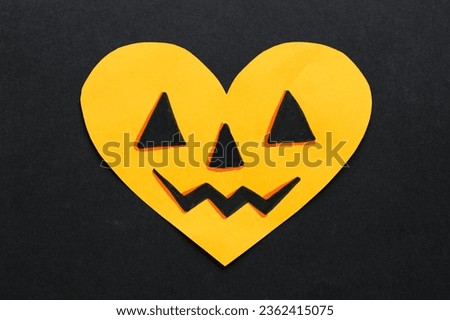 orange heart shaped paper card with a halloween pumpkin face on a black background