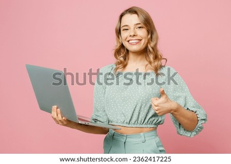 Young smiling satisfied happy IT woman wearing casual clothes hold use work on laptop pc computer show thumb up like isolated on plain pastel light pink background studio portrait. Lifestyle concept