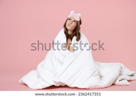Puzzled confused young woman in pajamas home wear sleep mask sit wrapping in blanket looking up resting at home isolated on pastel pink background studio portrait. Relax good mood lifestyle concept Royalty-Free Stock Photo #2362417351