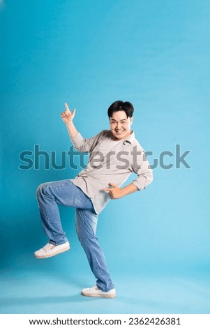Full body image of Asian man posing on blue background