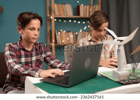 Smart children work as a team using laptop computer to program wind turbines. Brothers making wind project learning about eco-friendly forms of renewable energy at home. Copy space Royalty-Free Stock Photo #2362437161