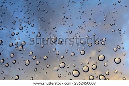 a photography of a bunch of water droplets on a window, bubbles of water are on a window glass as the sun sets.