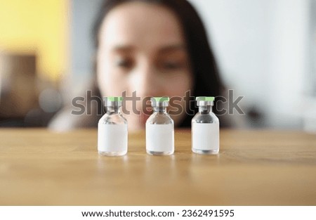 Woman looks at vaccine bottle and decides which one to choose. Comparison of coronavirus vaccines concept Royalty-Free Stock Photo #2362491595