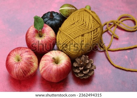 Cozy autumn still life with red apples and woolen yarn balls. Hobby and leisure concept. 